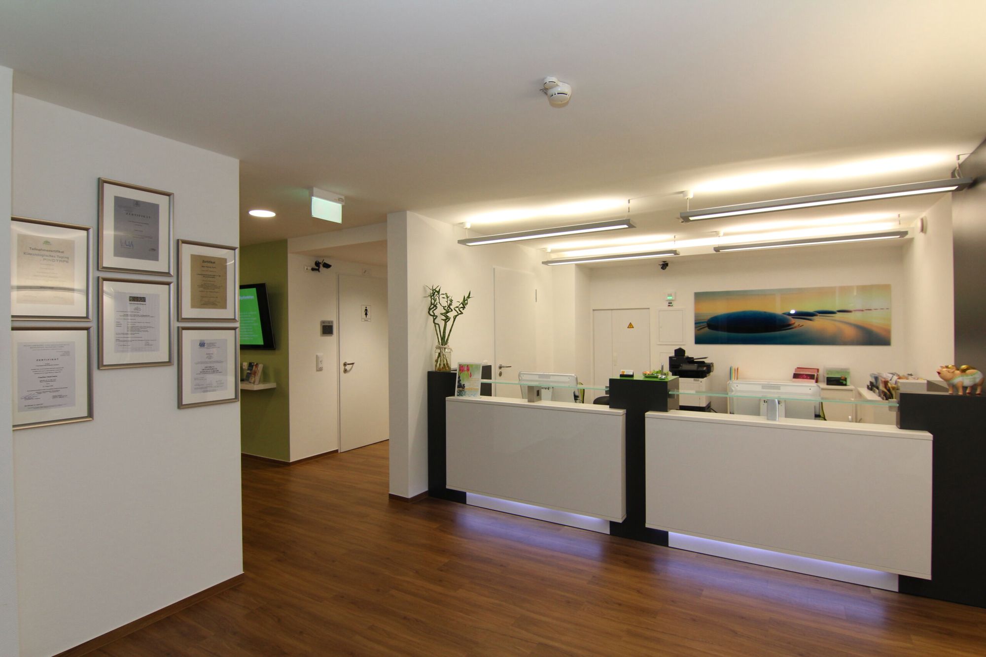 Heller Empfangstresen mit grüner Lichtleiste im Therapiezentrum Dentl
